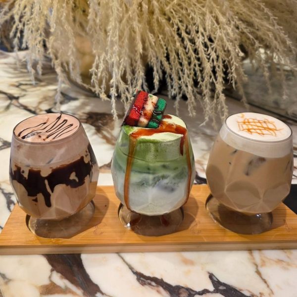 Three signature specialty lattes on the marble bar at Crave Café